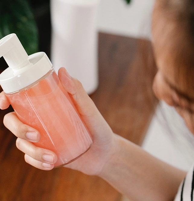 A person holding an empty bottle of lotion.